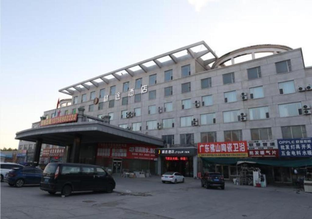 长春JTOUR Inn Qingnian Road Zhubang Plaza Yanming Lake的停车场内停放汽车的大型建筑