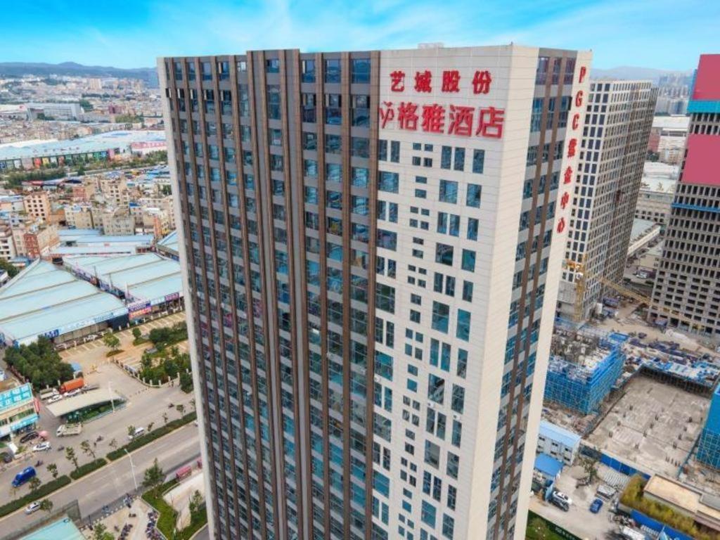昆明Gya Hotel Kunming Zijin Center Xiaodongcun Metro Station的一座高大的建筑,在建筑的一侧写字