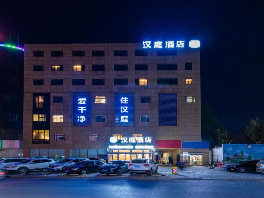 济南Hanting Hotel Jinan Guo Branch的停车场内有许多车辆的建筑物