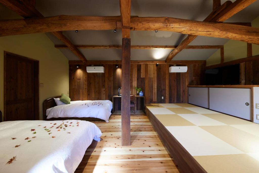 丰冈市ゲストハウス長閑的配有木地板和木梁的客房内的两张床