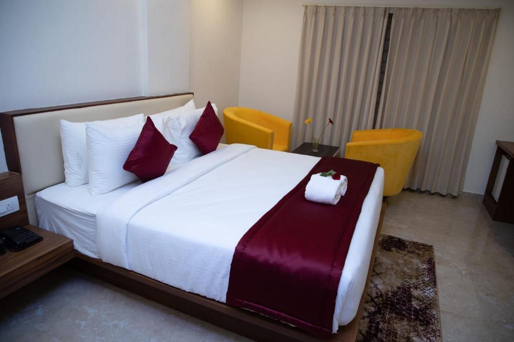 班加罗尔ZIONS AIRPORT HOTEL AND APERTMENT! Near Kempegowda International Airport的卧室配有带红色枕头的大型白色床