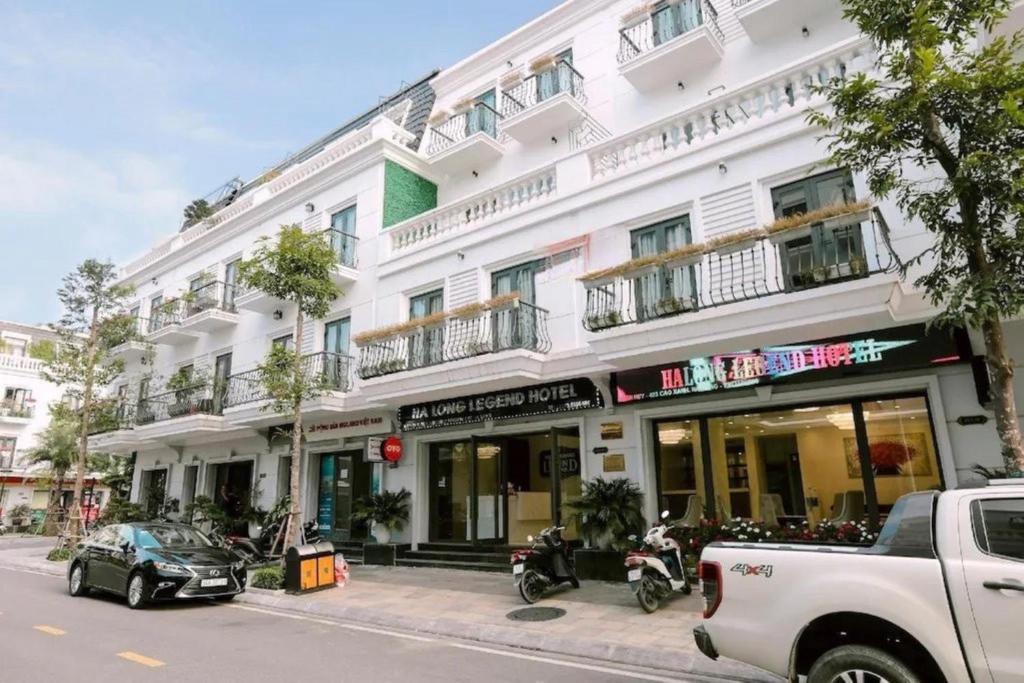 下龙湾Hạ Long Legend Hotel的一座白色的建筑,前面停有摩托车