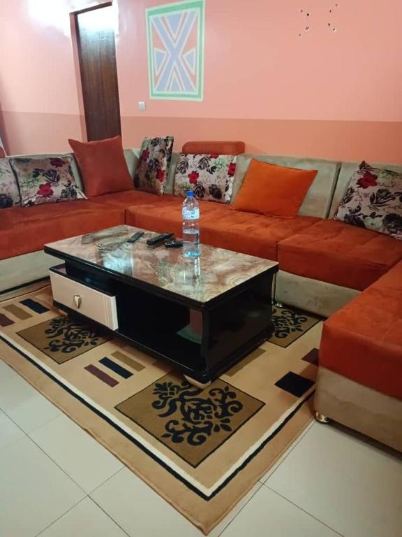 博博迪乌拉Résidence privée的带沙发的客厅和桌子上的一瓶水