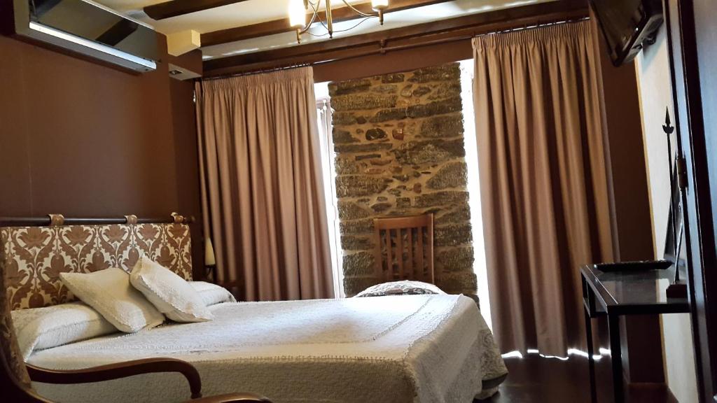 蒙福特·德·莱蒙斯Hostal Medievo的卧室在石墙前配有一张床