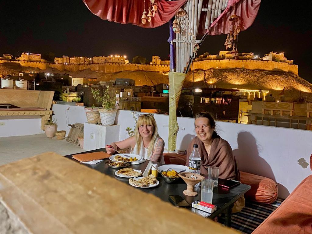 斋沙默尔Hotel Murad Haveli Jaisalmer的坐在餐桌旁吃饭的男人和女人