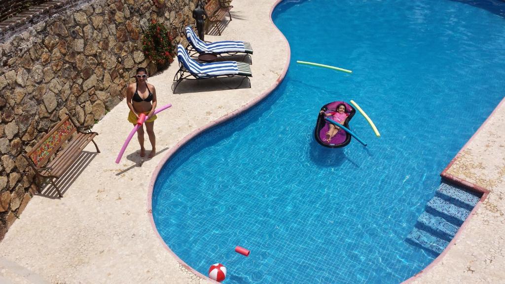 阿卡普尔科Villa Costa Chica Comodisimo piscina gigante jardines的身着泳衣的人站在游泳池旁