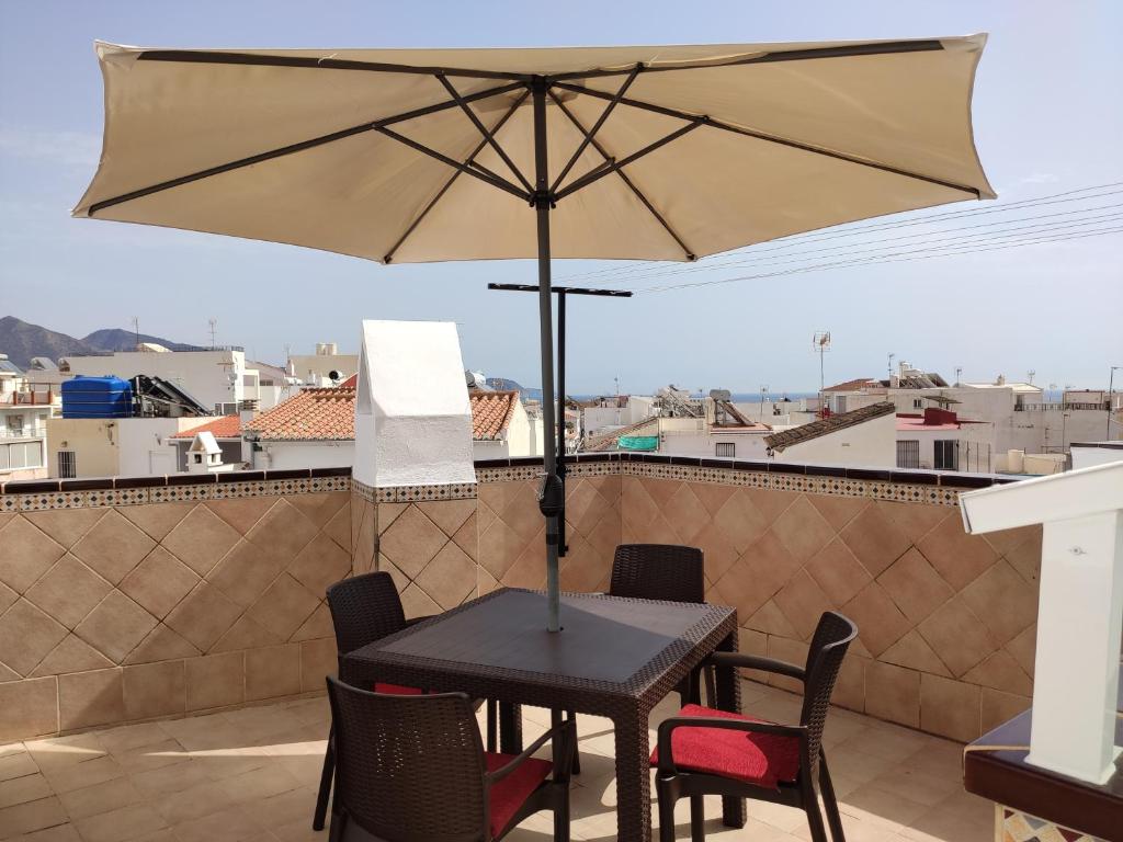 内尔哈Hostal Ana - Adults Recommended的阳台配有桌椅和遮阳伞