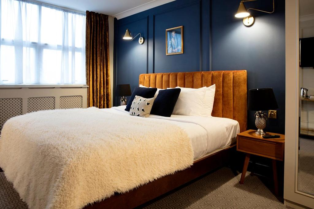 斯蒂夫尼奇Hotel Cromwell Stevenage的一间卧室配有一张带蓝色墙壁的大床