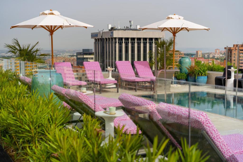 马德里Hotel Pinar Plaza的一个带粉红色椅子的阳台和一个游泳池