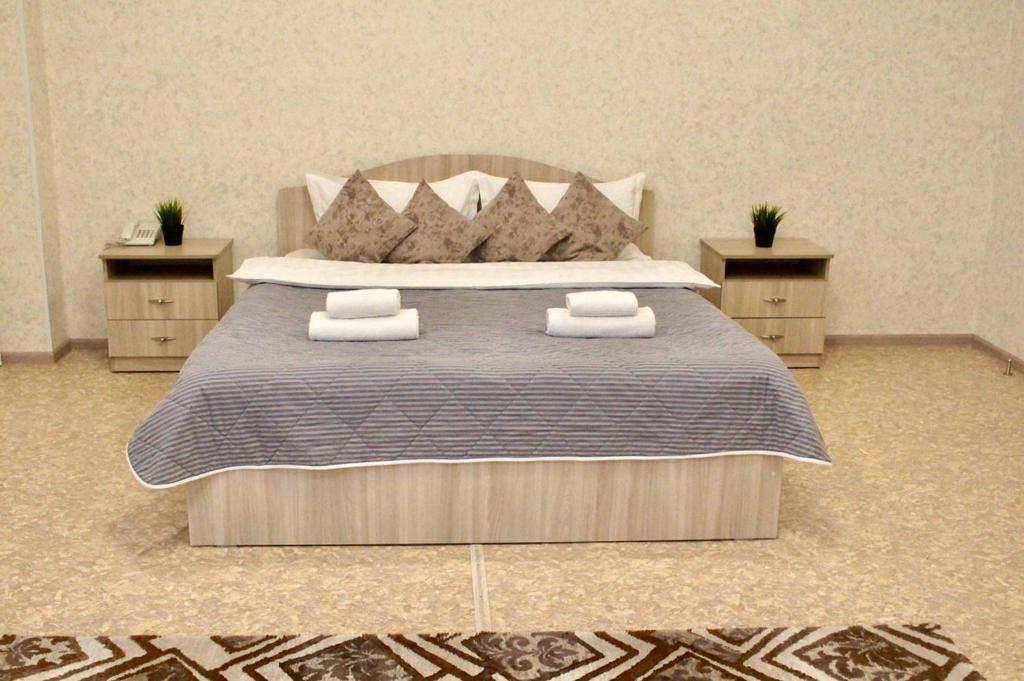 巴甫洛达尔гостиница Павлодар的一间卧室配有一张带2个床头柜的大床