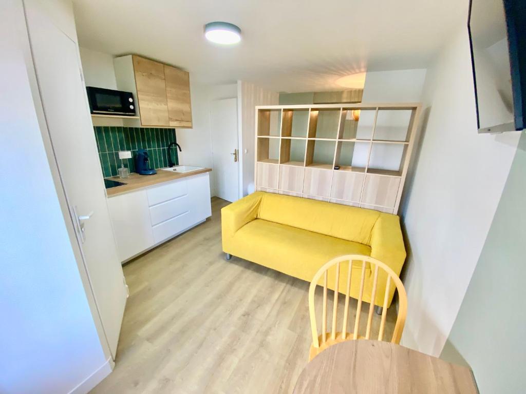 勒阿弗尔L'Escale Appartements et Suites en bord de Mer的一间带黄色沙发的客厅和一间厨房