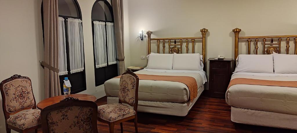 波托西Hostal Colonial Potosi的一间卧室配有两张床、两把椅子和一张桌子