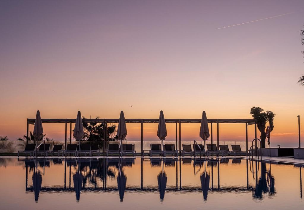 贝纳尔马德纳伊斯迪瓦托克布拉德酒店的一个带遮阳伞和椅子的水池