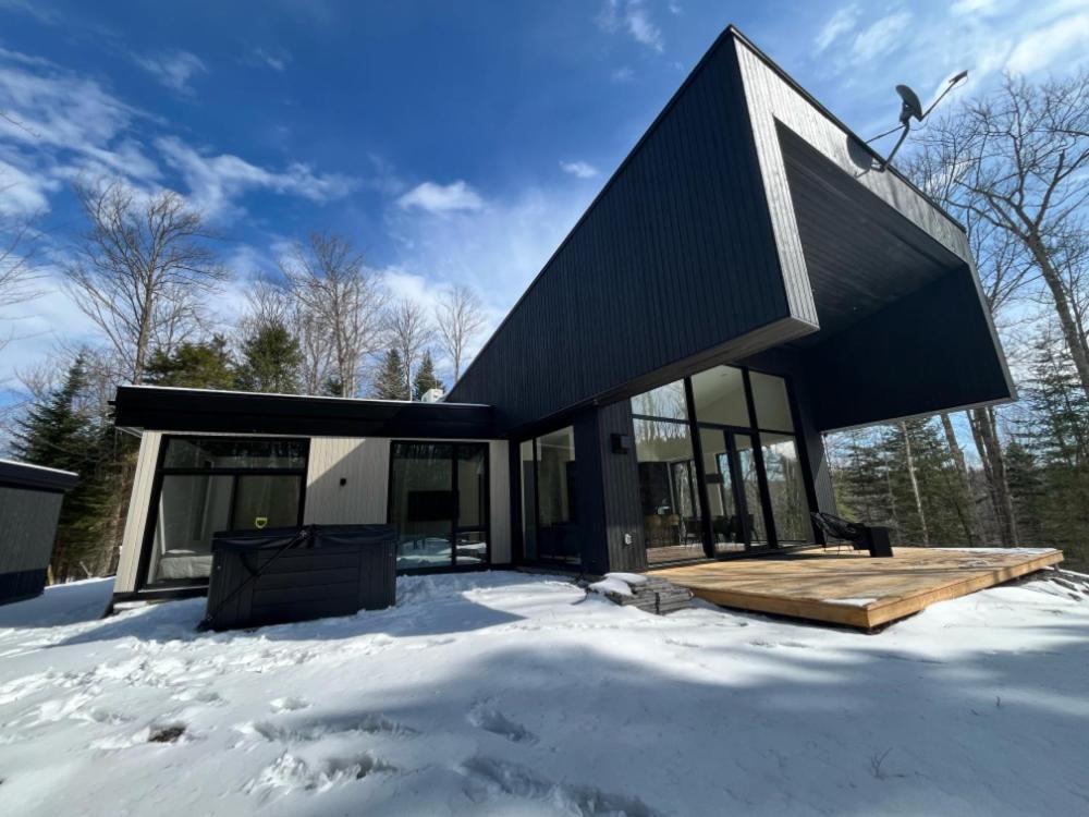 St-Etienne de BoltonAu Haut De La Colline Spa Et Sauna的雪中带黑色屋顶的房子