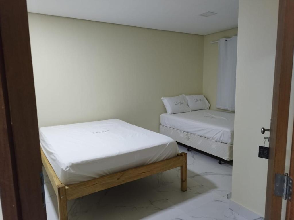 GamaLONDRES HOTEL的白色墙壁客房的两张床