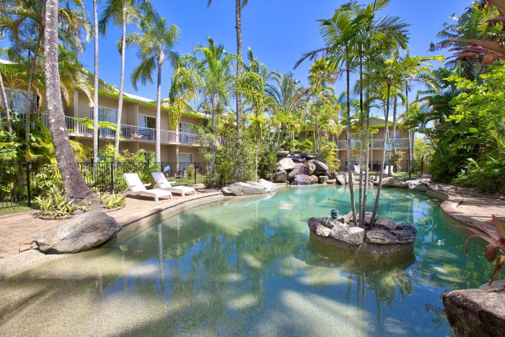 凯恩斯Hotel Tropiq的棕榈树度假村内的游泳池