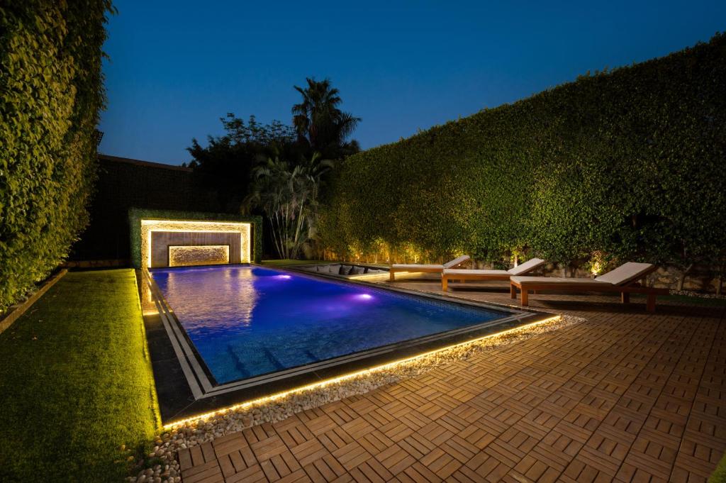 开罗Zyra villa with pool and waterfall in New Cairo的夜间后院的游泳池