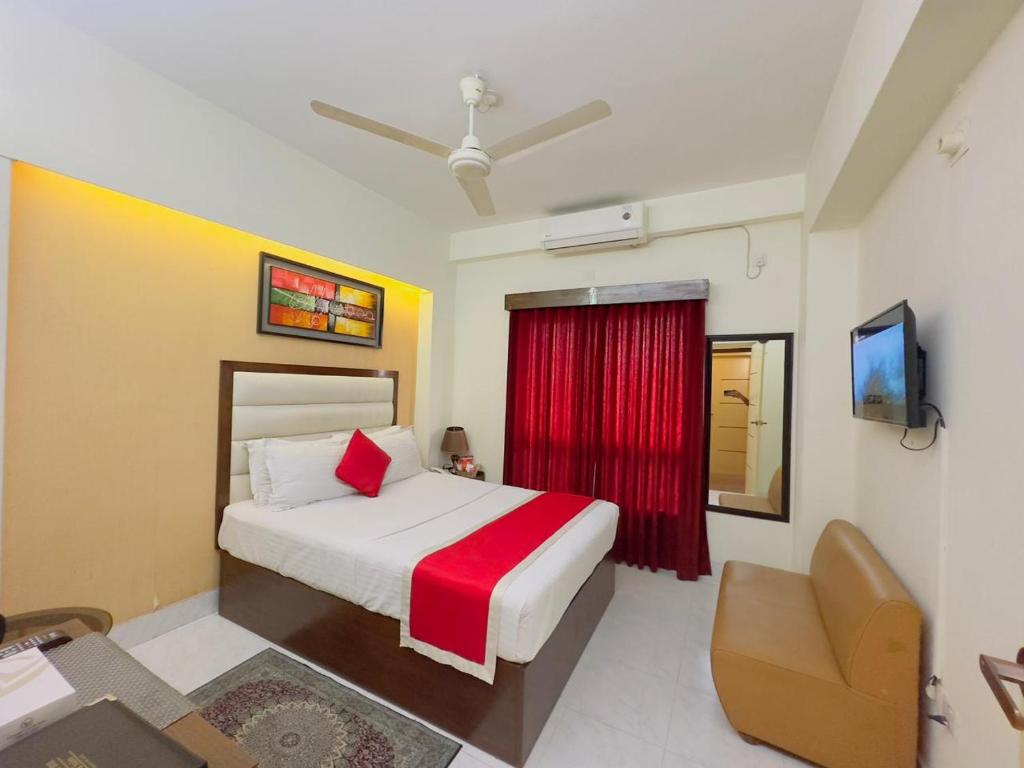 达卡Hotel Grand Circle Inn Dhaka的一间卧室配有一张床、一把椅子和电视