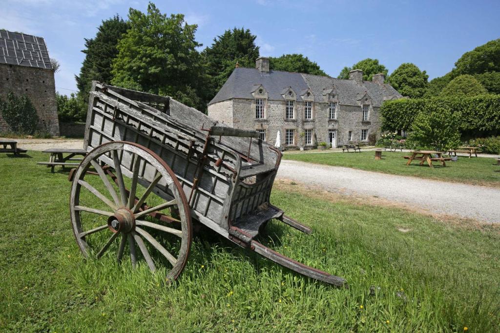 CarnevilleGite du Manoir des Anoteux的坐在建筑物前面的草上的一个木车