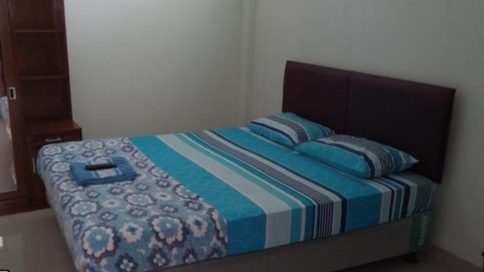 LampungCut Nyak Dien Guest House的一间卧室配有一张带蓝色毯子和枕头的床。