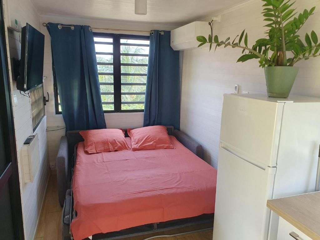 RémiréLes Maripas T2的小型客房内的一张小床,配有冰箱