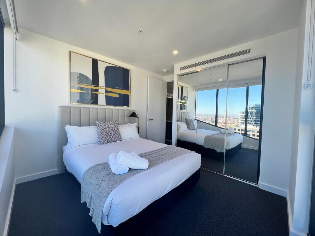 墨尔本Samma Flagstaff Luxury Apartments的一间带一张白色大床的卧室和一个阳台