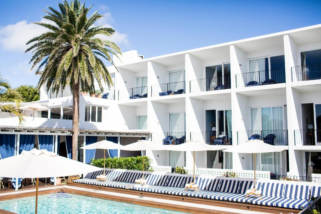 卡巴雷塔海滩Halcyon House的一座拥有游泳池、棕榈树和遮阳伞的酒店