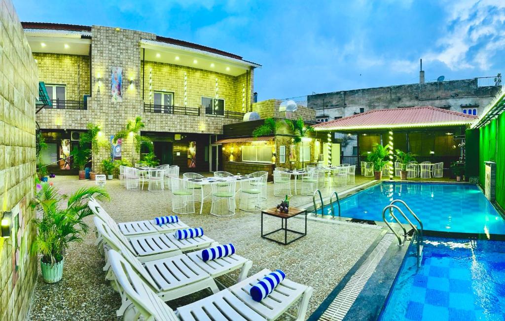 乌代浦Hotel Grand Bhagwat, Udaipur的一个带白色躺椅和游泳池的庭院