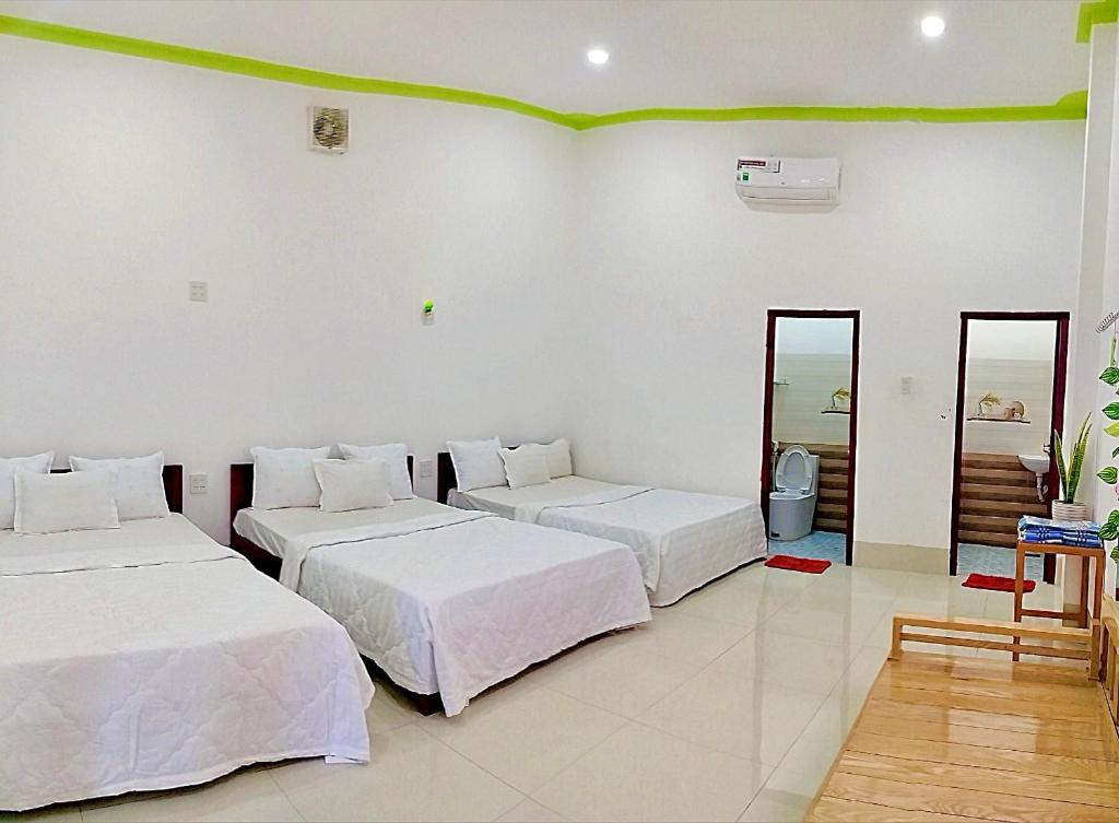 潘切Homestay Châu Triều - Phan Thiết的白色墙壁客房的两张床