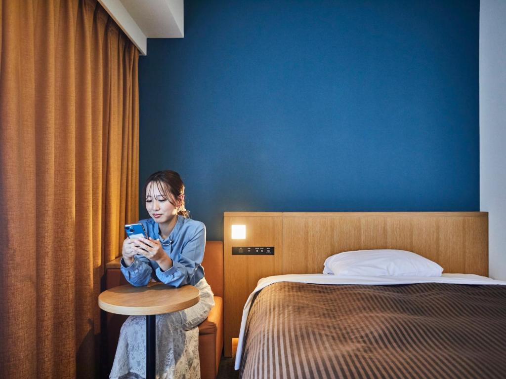 泉佐野关西机场华盛顿酒店的坐在酒店房间看手机的女人