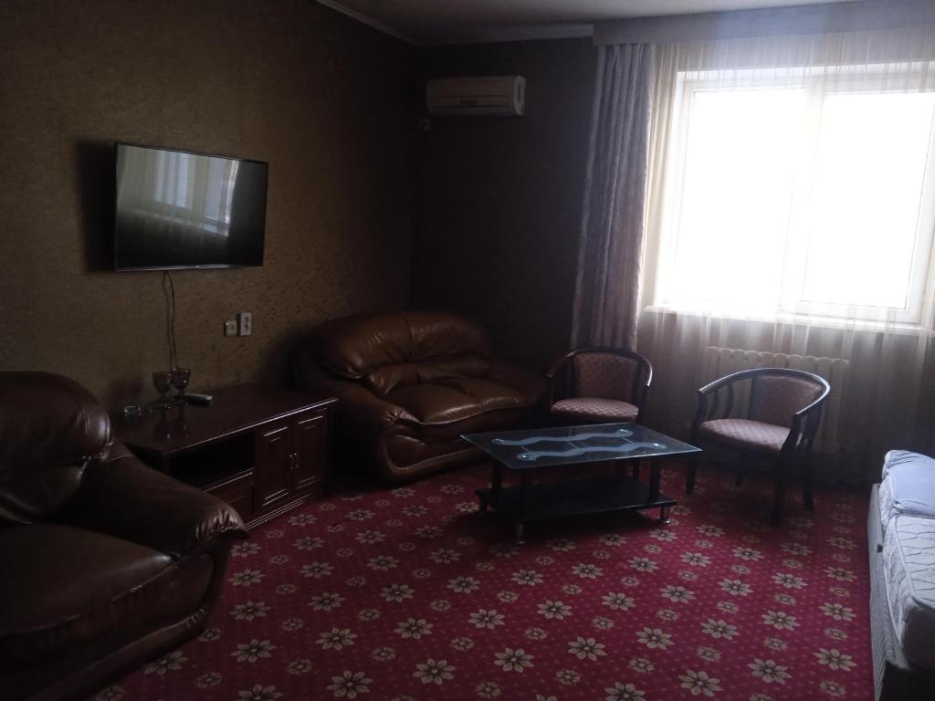 奇姆肯特ОРДА的客厅配有皮革家具和电视