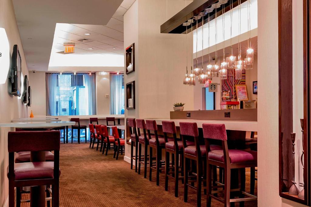 纽约纽约曼哈顿/时代广场万怡酒店的餐厅设有红色椅子和酒吧