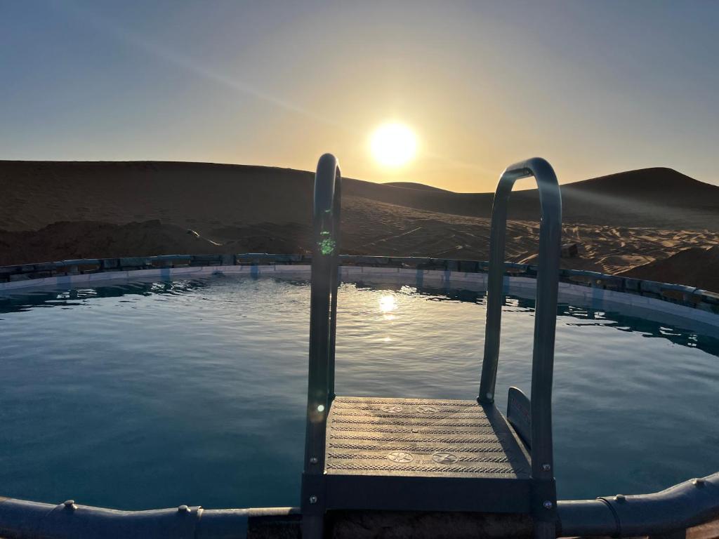 梅尔祖卡Sahara Majestic Luxury Camp的小型游泳池,设有木制长凳