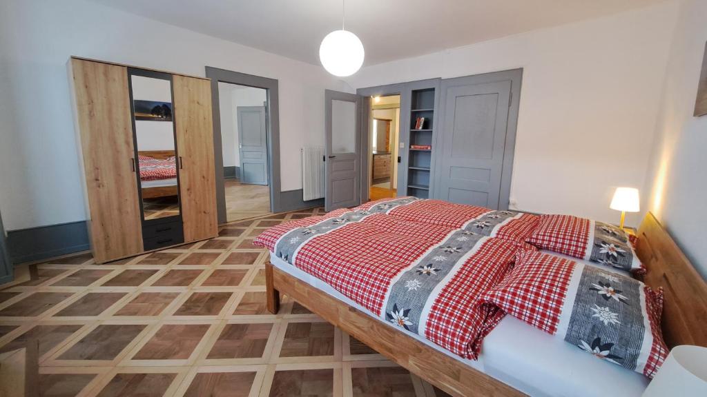 Saint-ImierAppartement de vacances Les Jardins的一间卧室配有一张红色棉被的床