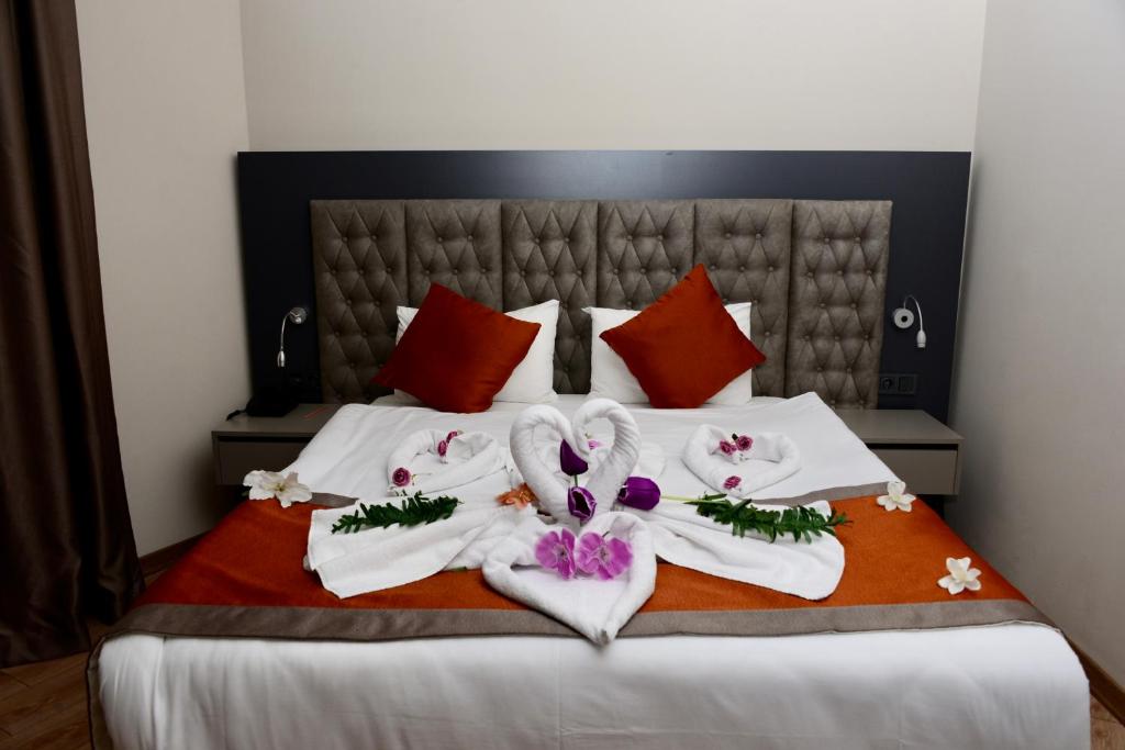锡德SiDE GOLDEN ROCK HOTEL&SPA的一张带白色毛巾和鲜花的床