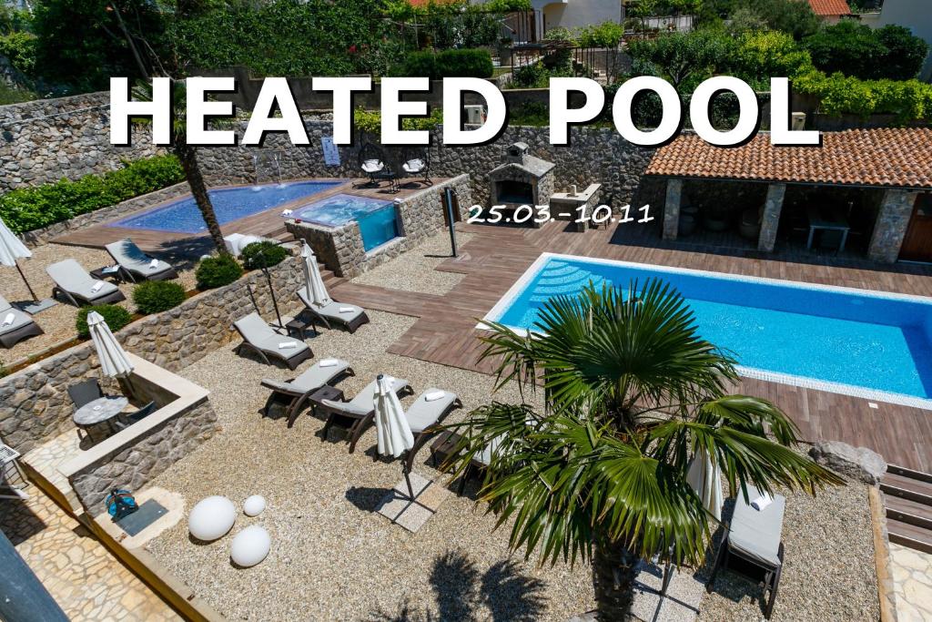 克尔克Villa Palma Krk的一个带椅子的温水游泳池,旁边是棕榈树
