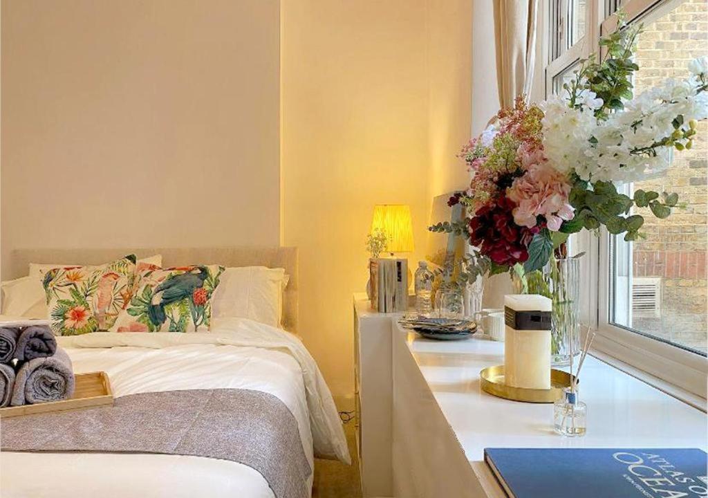 伦敦Tower Bridge Borough Market London Bridge House的一间卧室配有一张床和一张鲜花桌