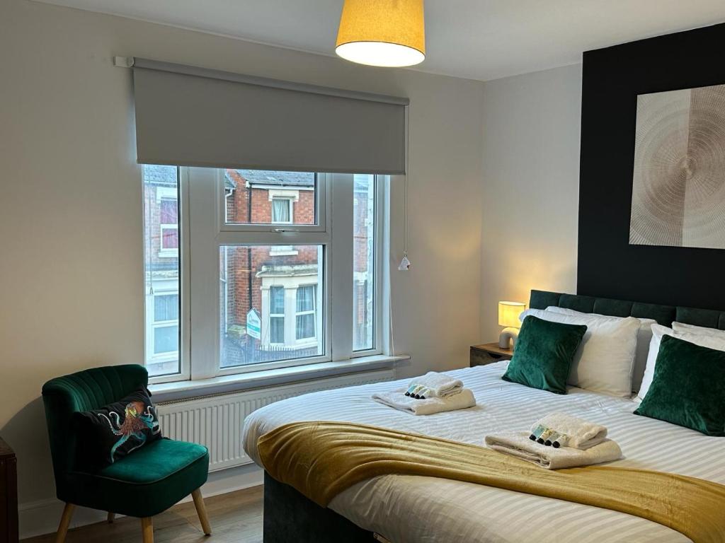 格洛斯特3 Bed Chill Glouc的一间卧室配有一张带绿椅的床和窗户