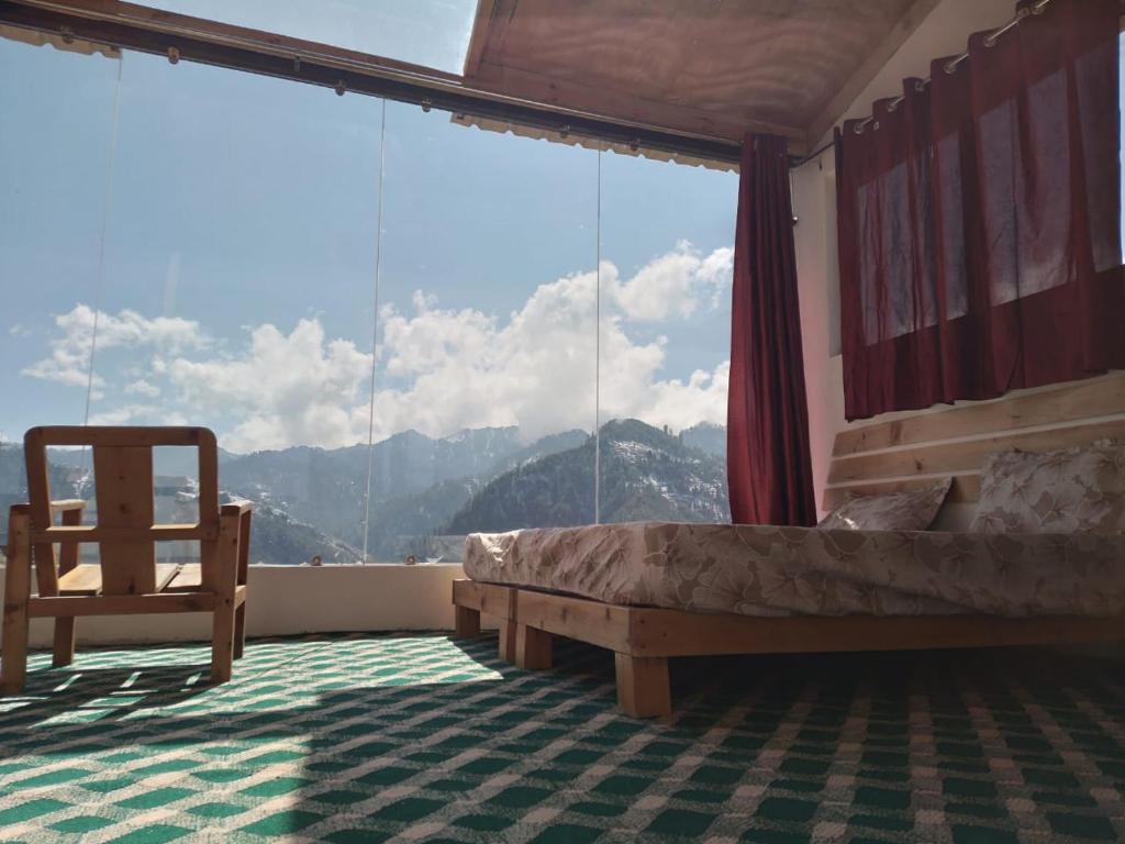 马恩迪Stargazing Glass Lodge Himachal Pradesh Thachi的卧室配有一张床和一张椅子,位于窗户前