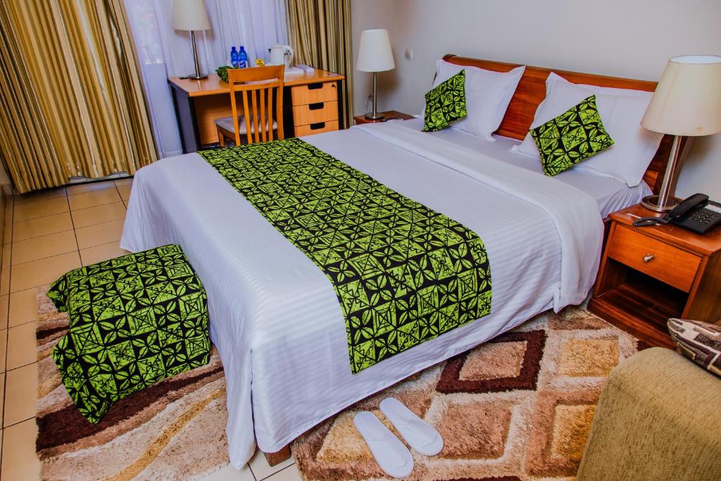 基加利One Click Hotel的一间卧室配有一张带绿色和白色床单的大床