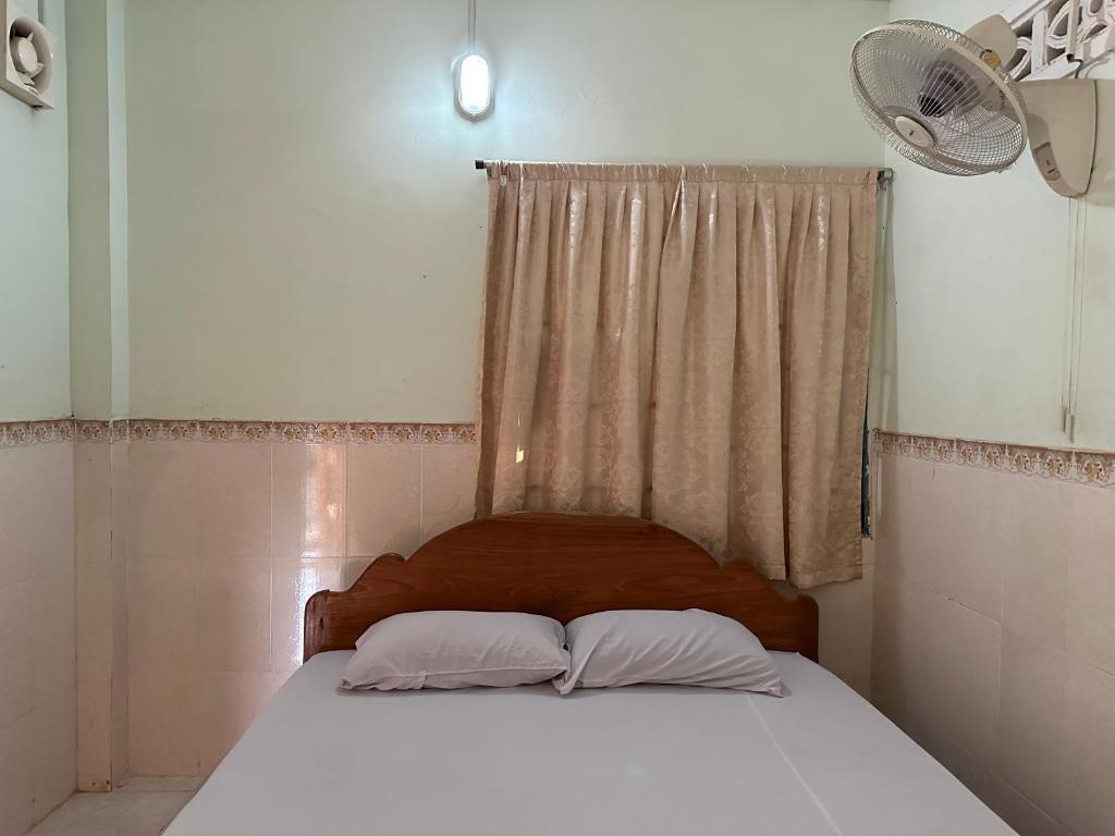 马德望Palm Tree Quest House的一间卧室配有带两个枕头的床和窗户