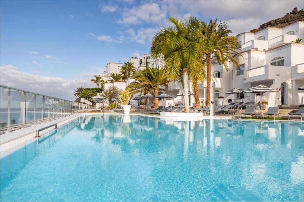 波多黎各大加那利岛海湾景码头公寓 - 仅限成人入住的一座棕榈树和建筑的大型游泳池
