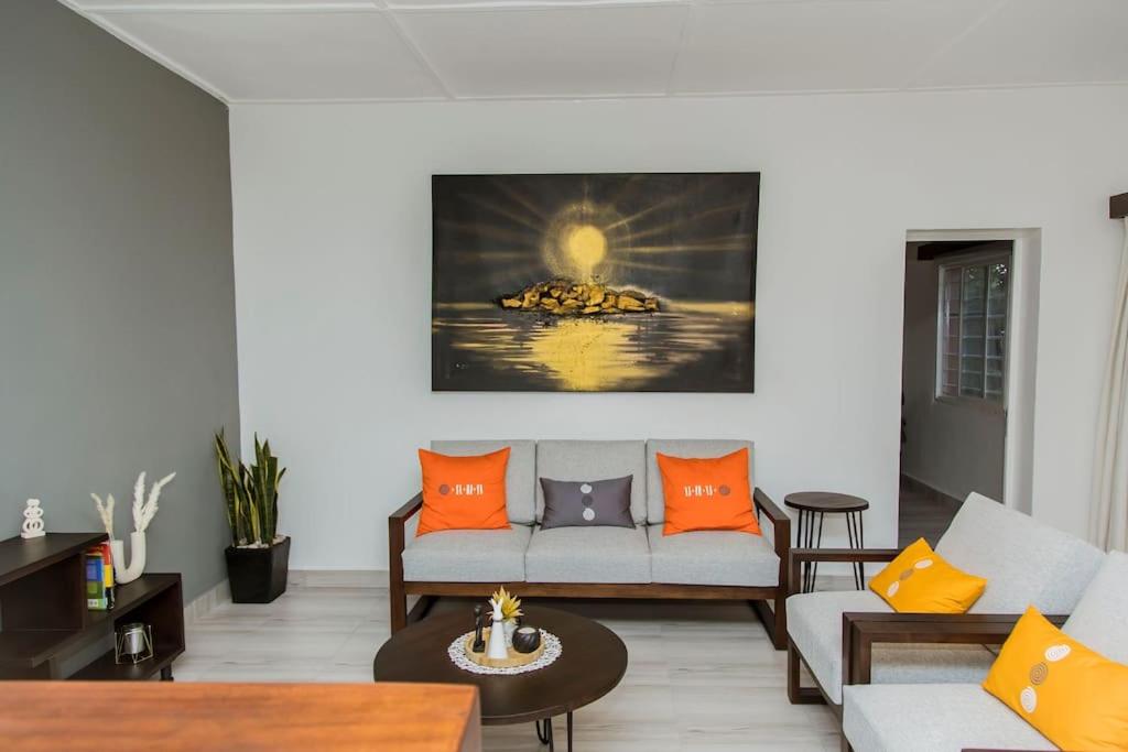 基加利Neza Haven Kigali的带沙发和橙色枕头的客厅