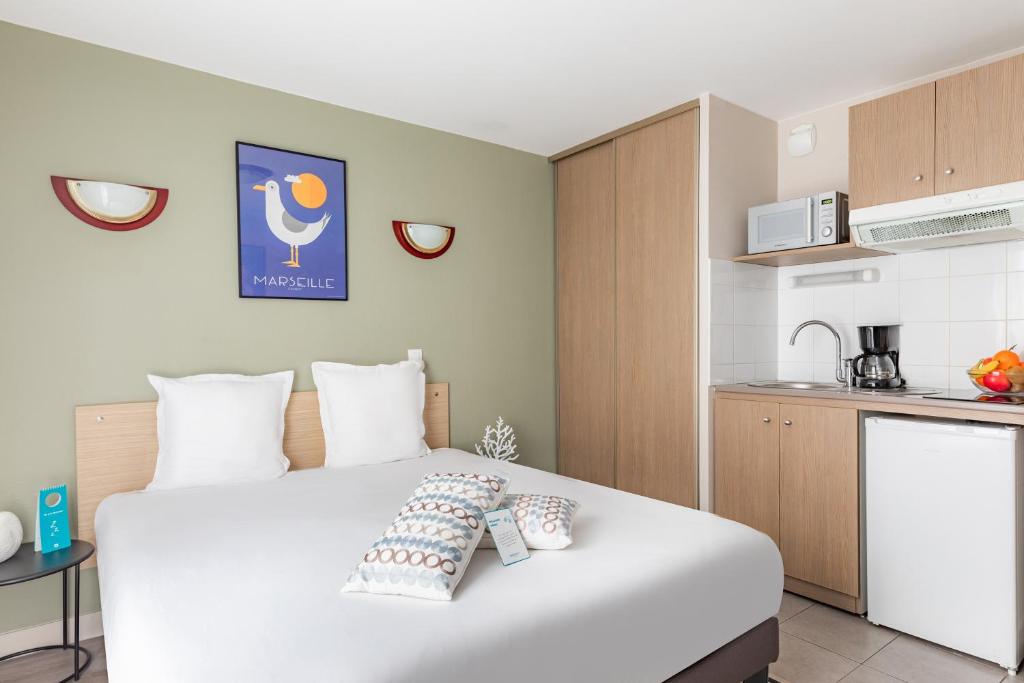 马赛Appart'City Classic Marseille Euromed的一间带白色大床的卧室和一间厨房