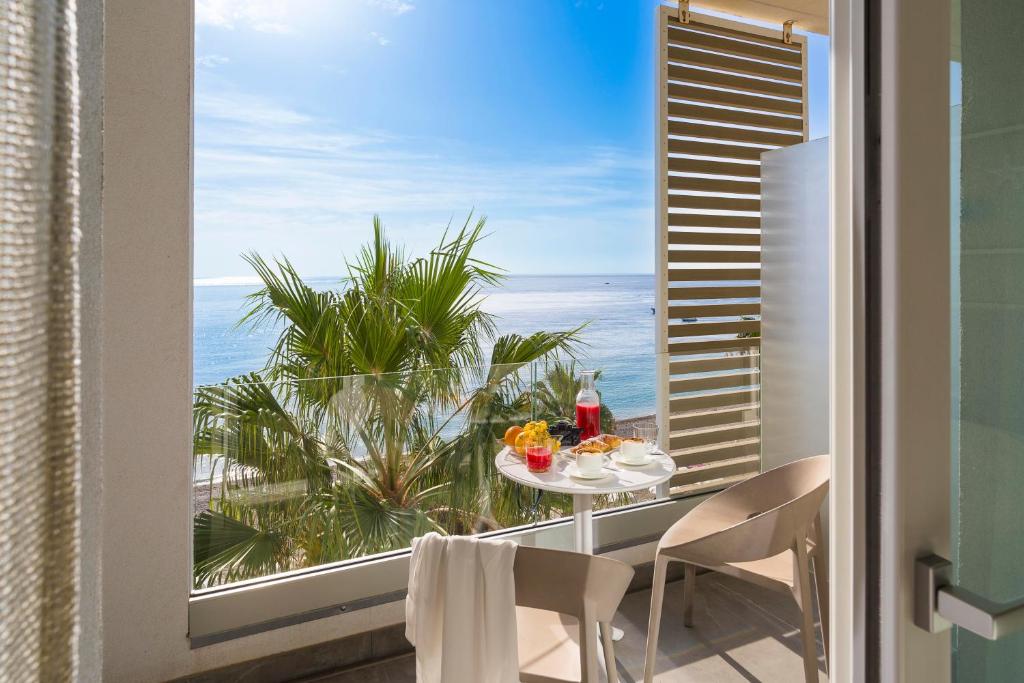 勒托阳尼Albatros Beach Hotel的海景阳台上的桌椅