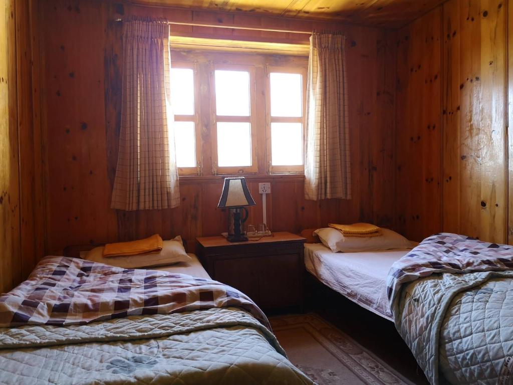 LuklaLukla Himalaya Lodge的木间设有两张床,设有窗户