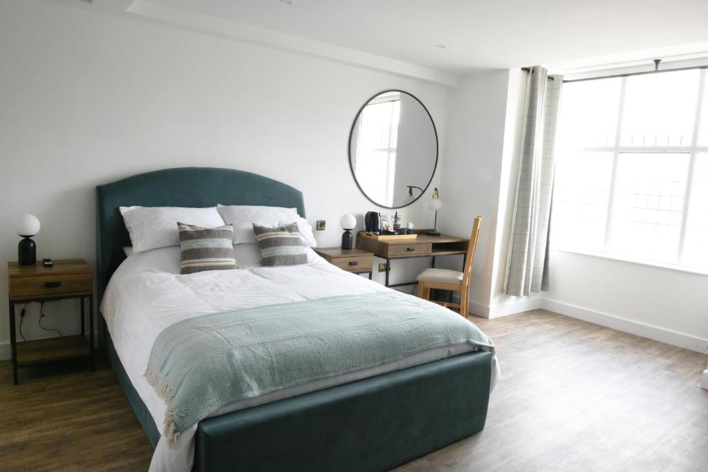 Woburn SandsThe Almshouse Suites的一间卧室配有一张带镜子的床和一张书桌