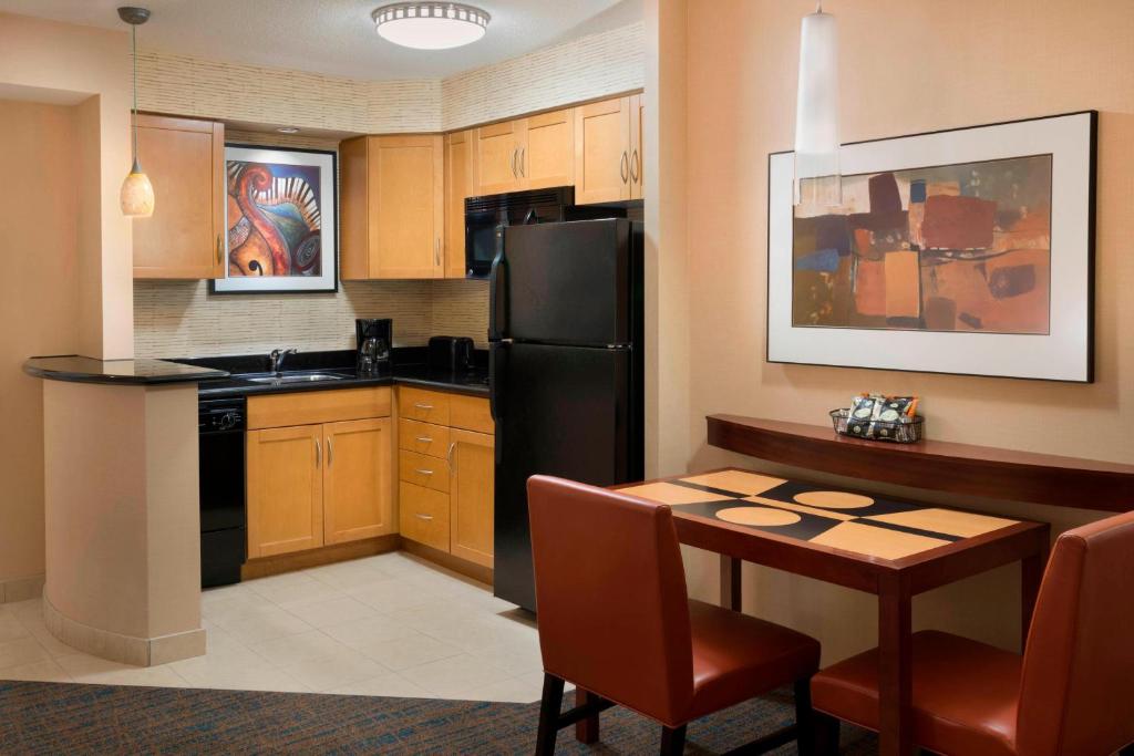 多伦多Residence Inn by Marriott Toronto Downtown / Entertainment District的厨房配有桌子和黑冰箱。