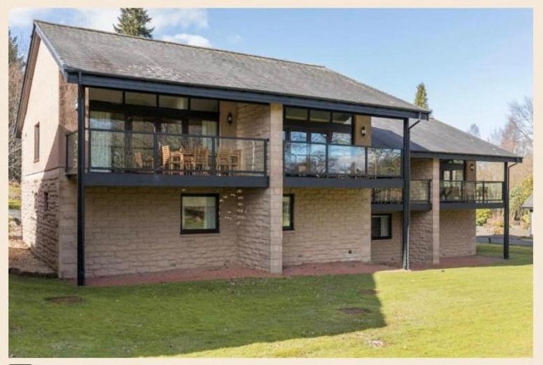 巴洛赫Cameron House - Lodge 17 - Loch Lomond的一座带甲板和阳台的大型砖砌建筑