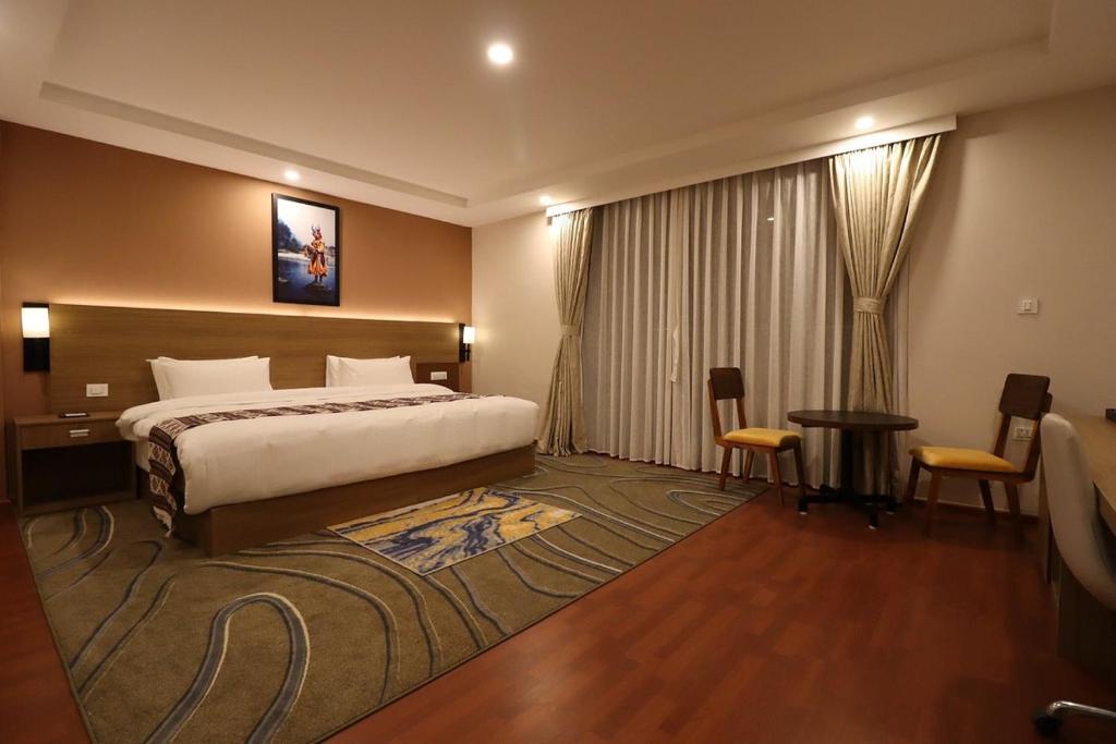 廷布Thimphu Deluxe Hotel的酒店客房带一张床、一张桌子和椅子